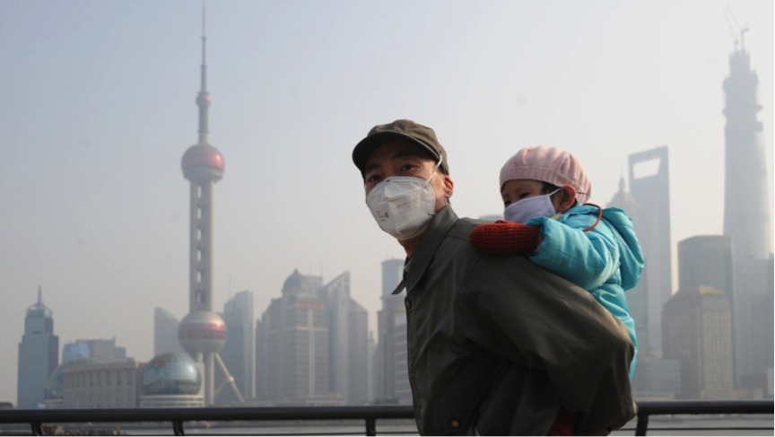 A man and child wear masks to visit Shanghai’s Bund. Via Creative Commons/CNN